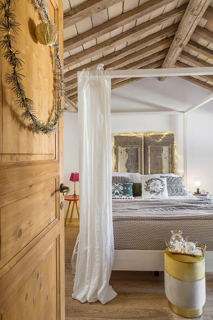 Blick auf Doppelbett mit Bettvorhang in ländlichem Schlafzimmer
