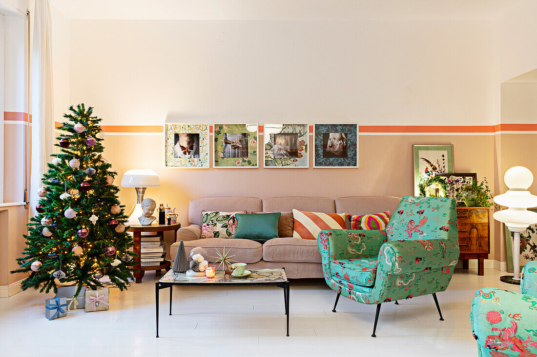 Retro armchair with colorful upholstery, coffee table, sofa, and Christmas tree in the living room