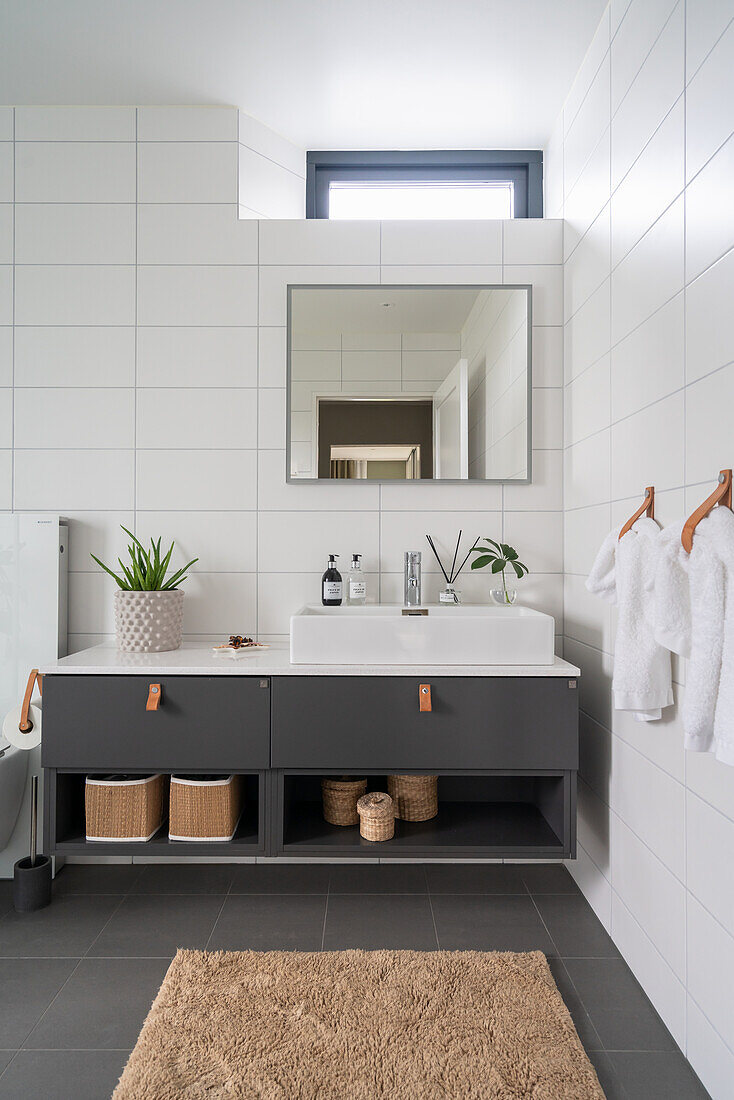 Waschtischmöbel mit Aufsatzbecken im Badezimmer mit weißen Wandfliesen