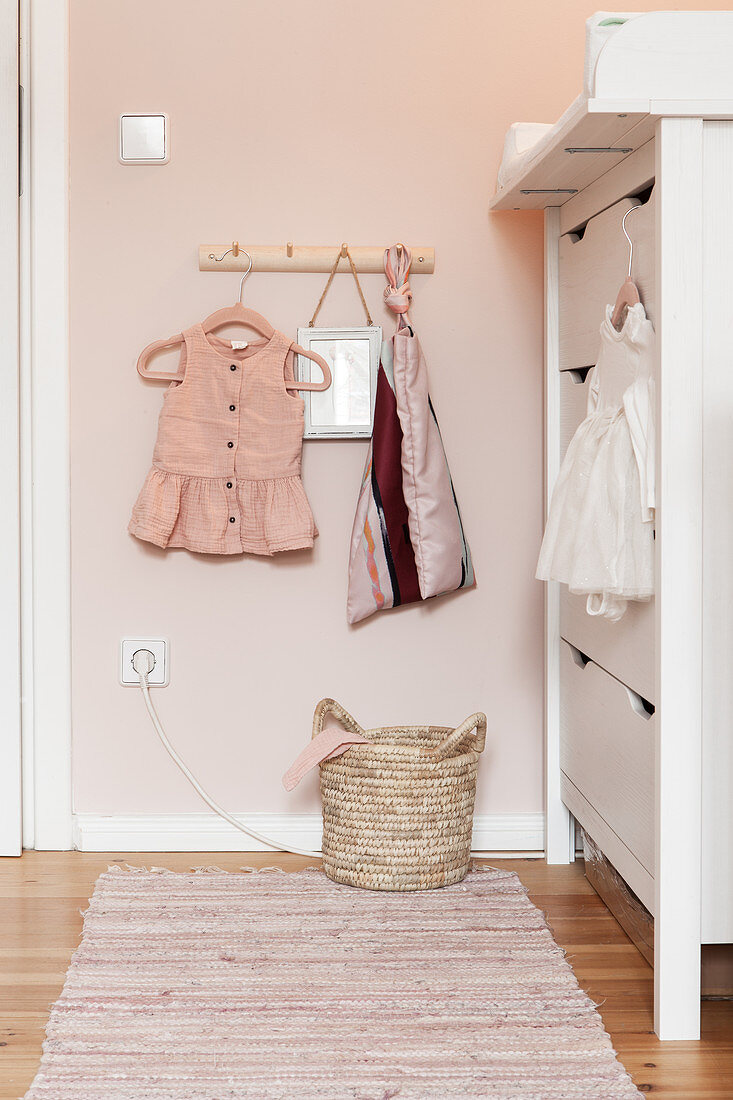 Baby clothes on coat rack next to changing unit