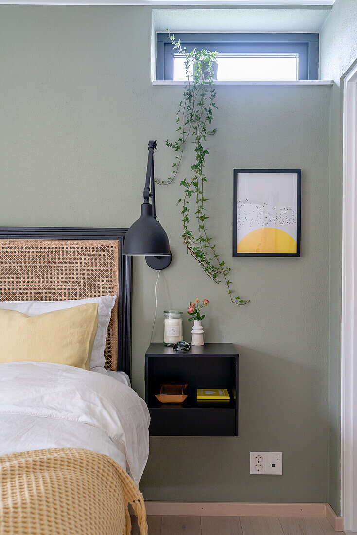 Wall mounted nightstand, wall lamp, and a cascading plant on windowsill in bedroom
