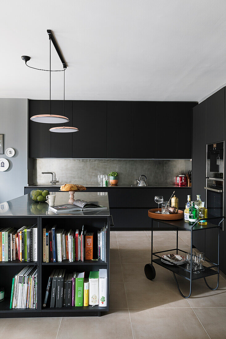 Black fitted kitchen cabinets, kitchen island with storage space for cookbooks and bar cart