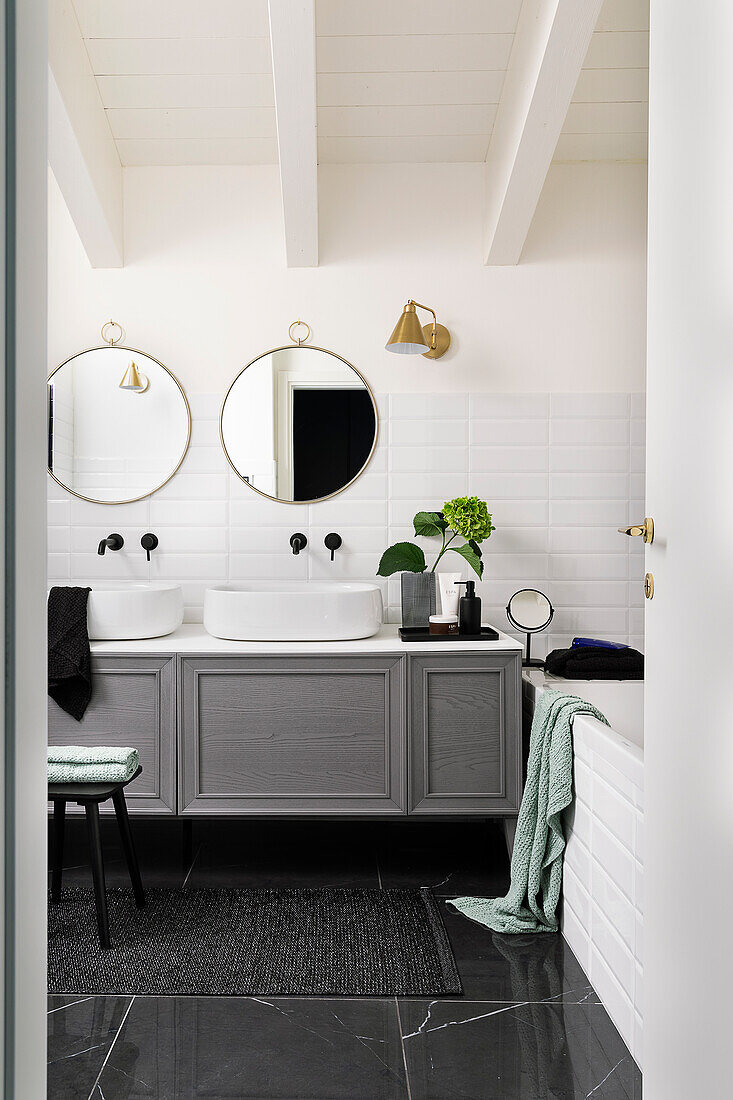 Waschtischmöbel mit zwei Aufsatzbecken, darüber runde Spiegel im Badezimmer