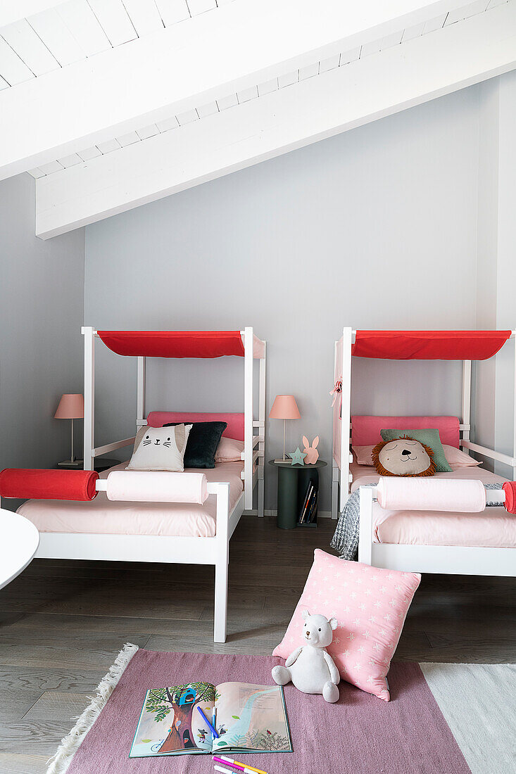 Teilweise überdachte Betten in Rosa und Rot im Geschwisterzimmer