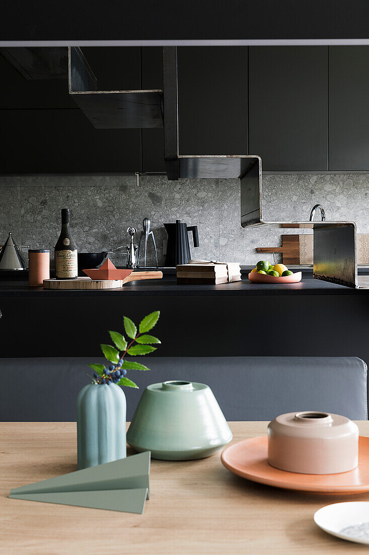 Keramikgeschirr auf Esstisch, im Hintergrund schwarze Kücheninsel