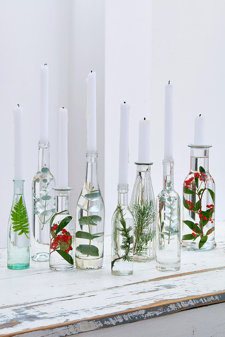 Upcycling idea: leafy branches in bottles filled with water used as decorative candlesticks