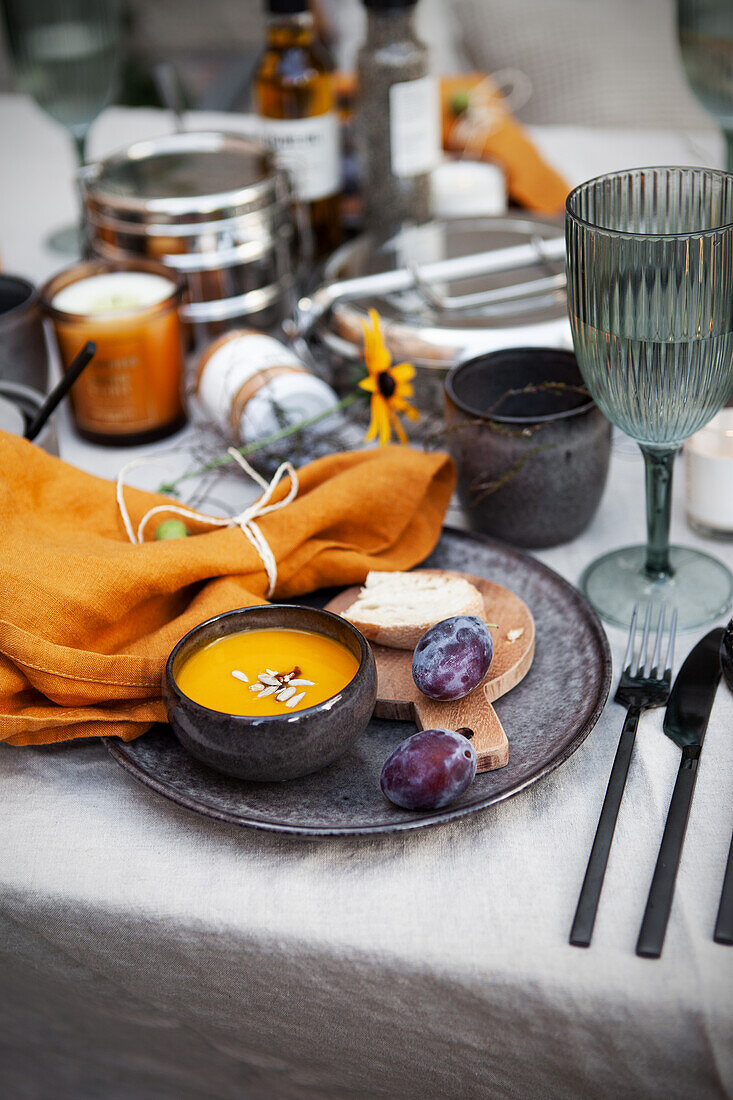 Herbstlich gedeckter Tisch mit Kürbissuppe und Pflaumen