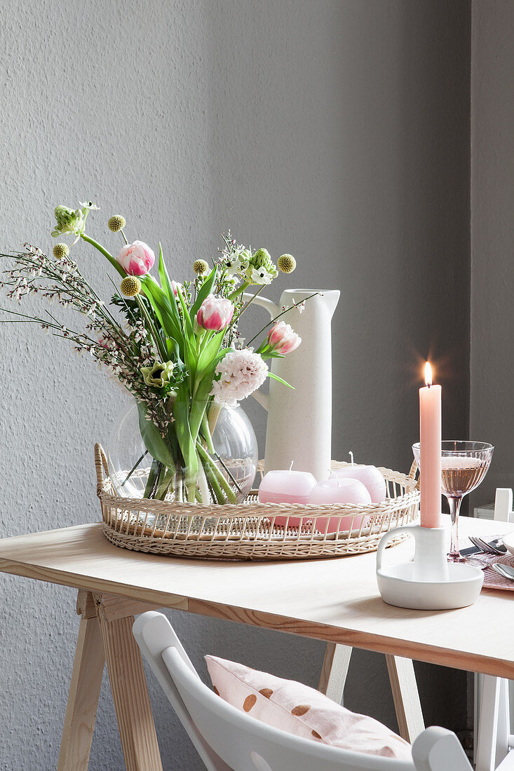 Frühlingsstrauß mit Tulpen und pastellrosa Kerzen auf Tisch