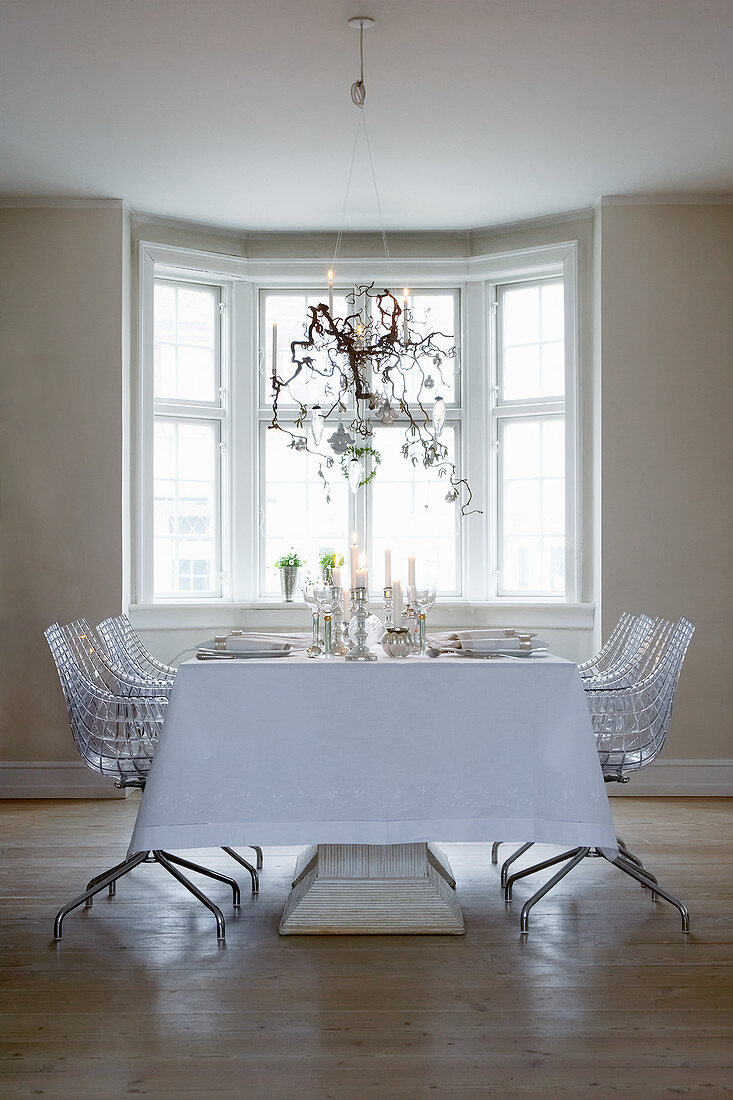 Table set in white for Christmas meal and designer chairs