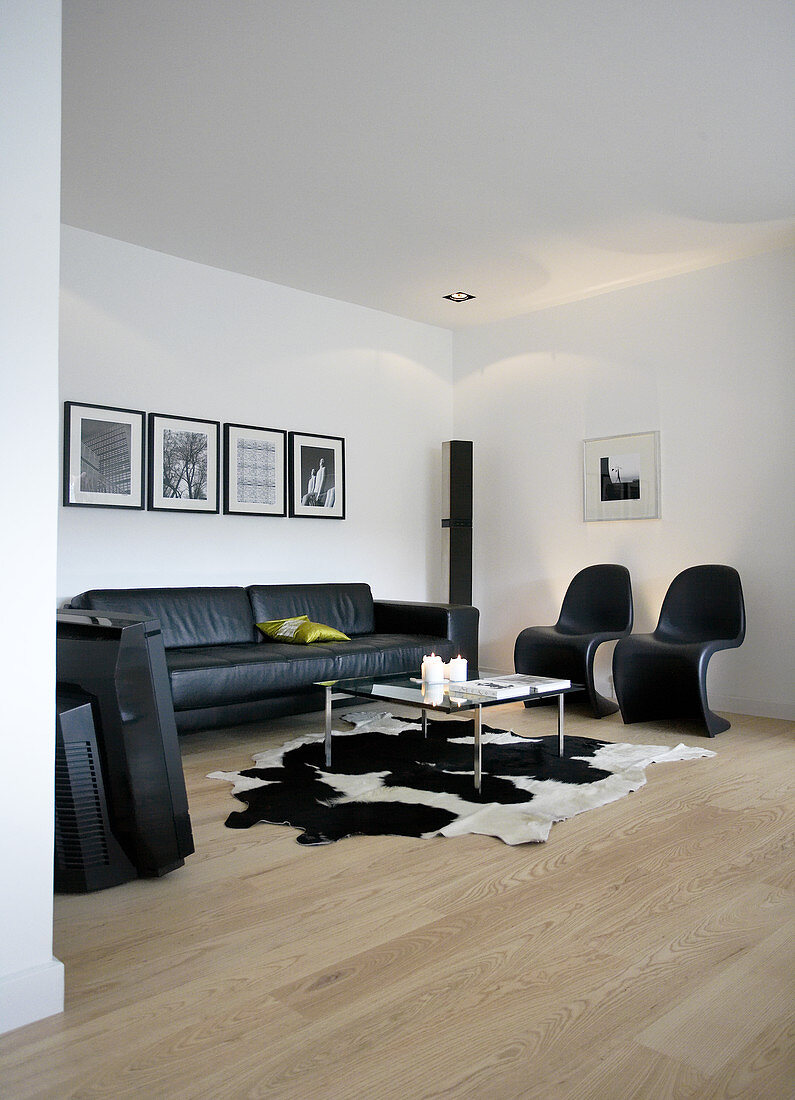 Schwarze Klassikerstühle, Ledersofa und Couchtisch auf Tierfell im Wohnzimmer