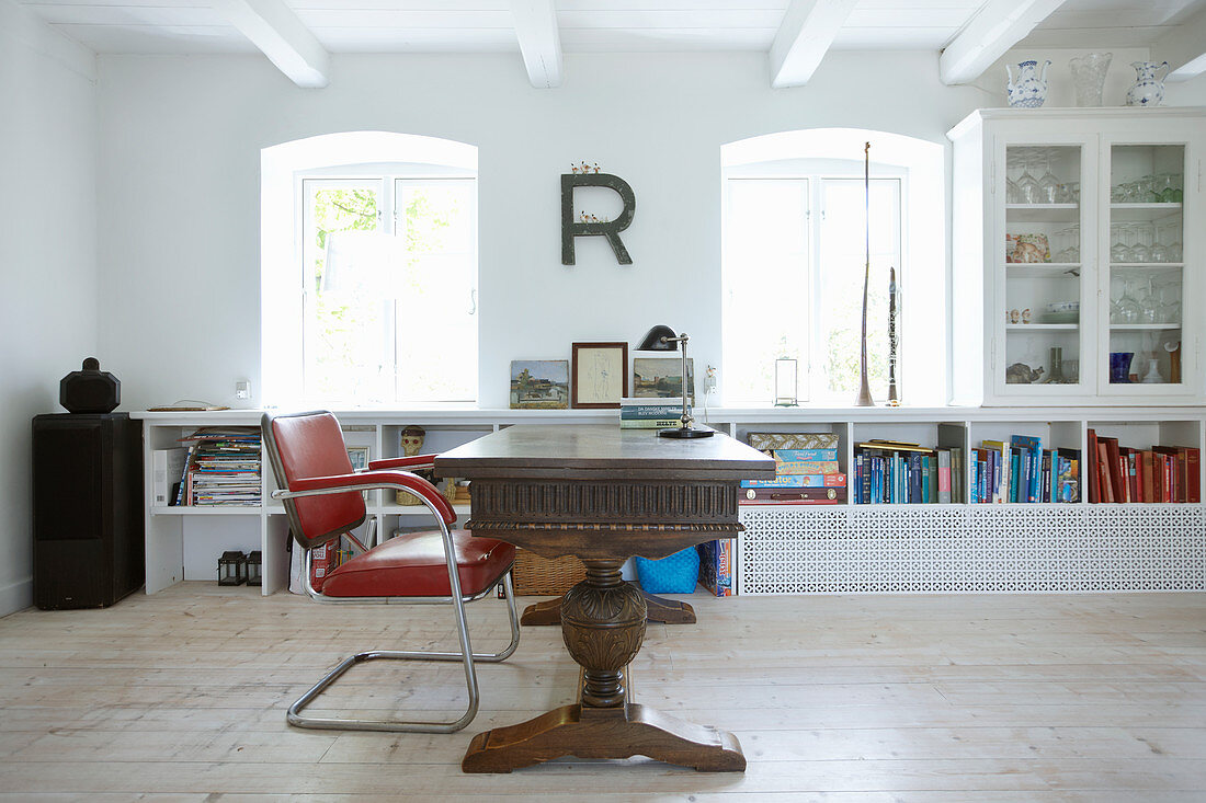 Solid wooden desk, red chair and white shelves in study