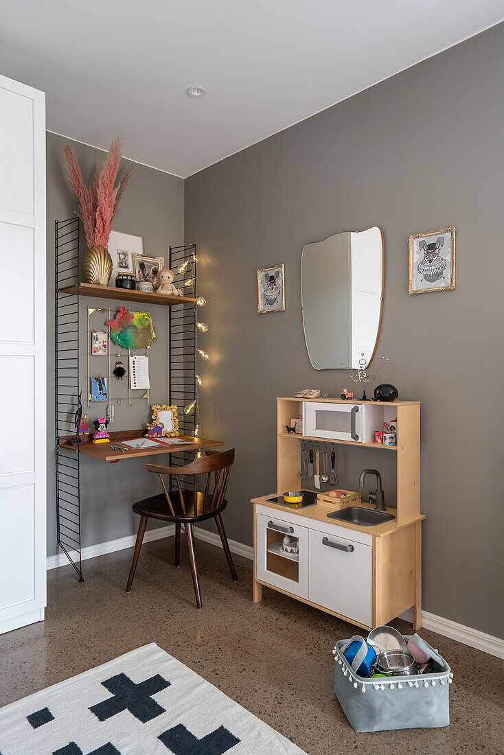 String shelves with integrated desk and play kitchen in room with grey walls