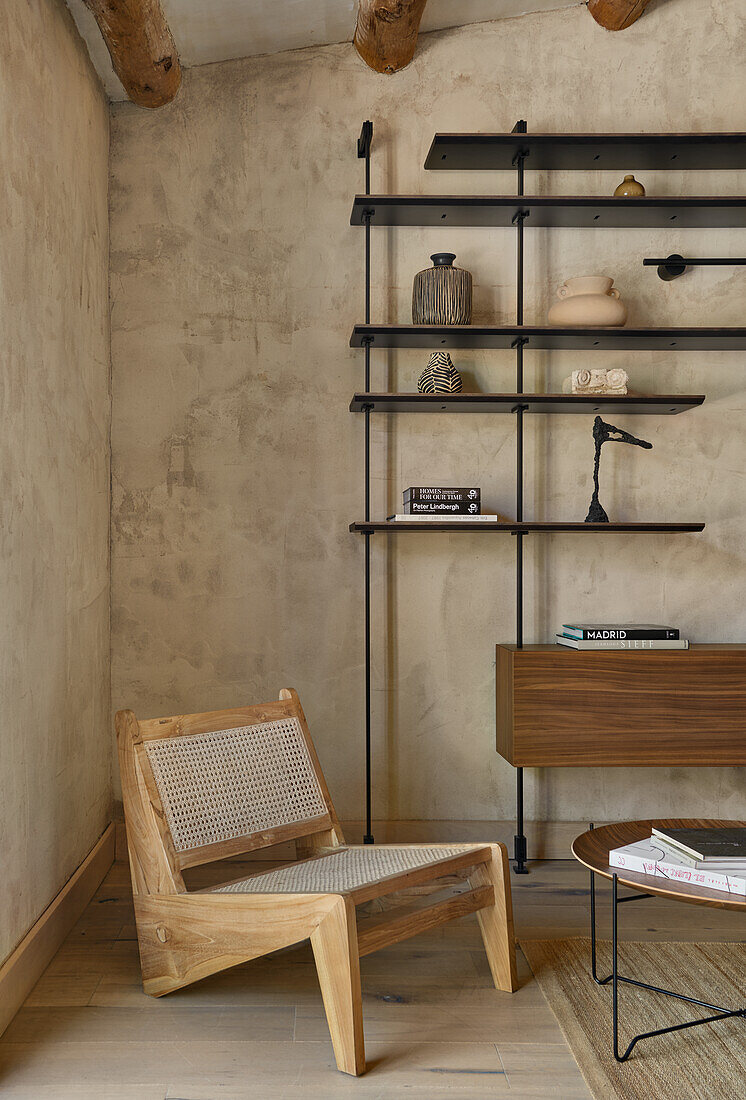 Designerstuhl und offenes Regal im Wohnraum mit sandfarbener Wand