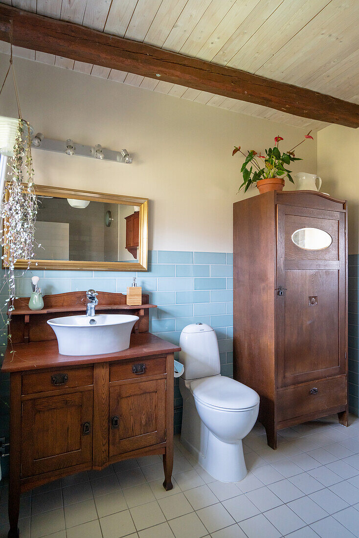 Antikes Waschtischmöbel, Toilette und Holzschrank im Badezimmer mit hellblauen Wandfliesen