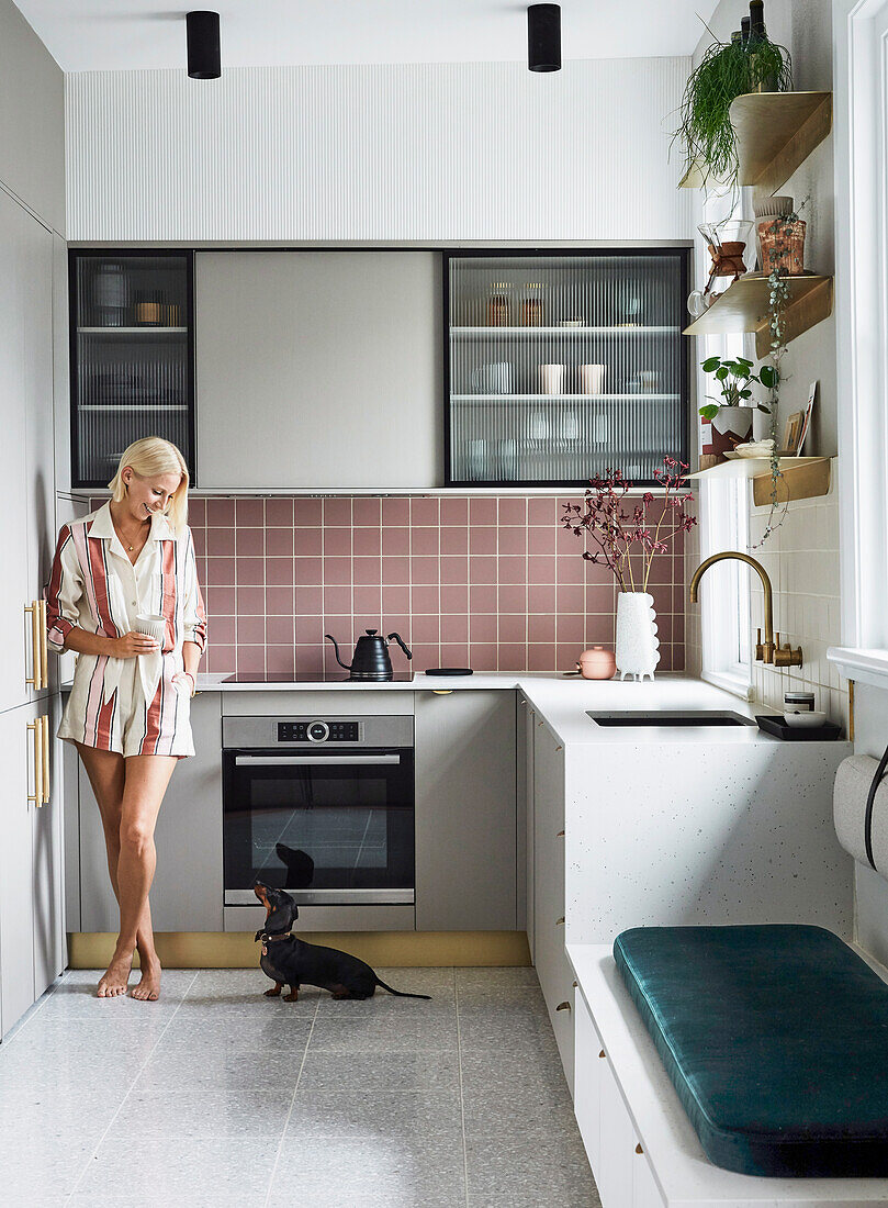 Blonde woman and dachshund in contemporary kitchen with bench seat