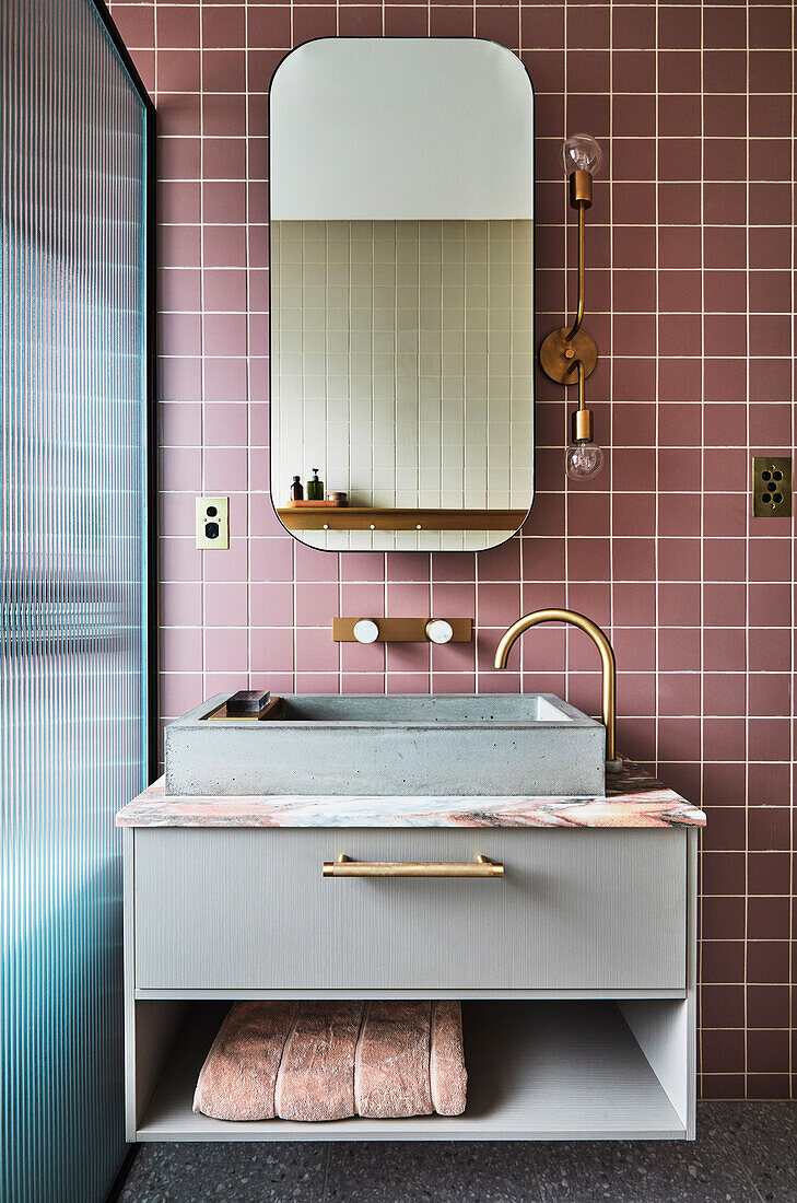 Waschtisch mit Aufsatzbecken im Badezimmer mit matt-rosa Wandfliesen