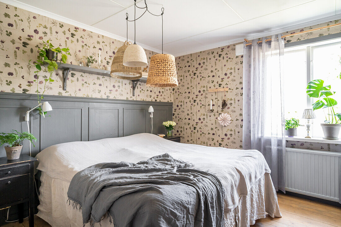 Doppelbett im Schlafzimmer mit Holzverkleidung und botanischer Tapete
