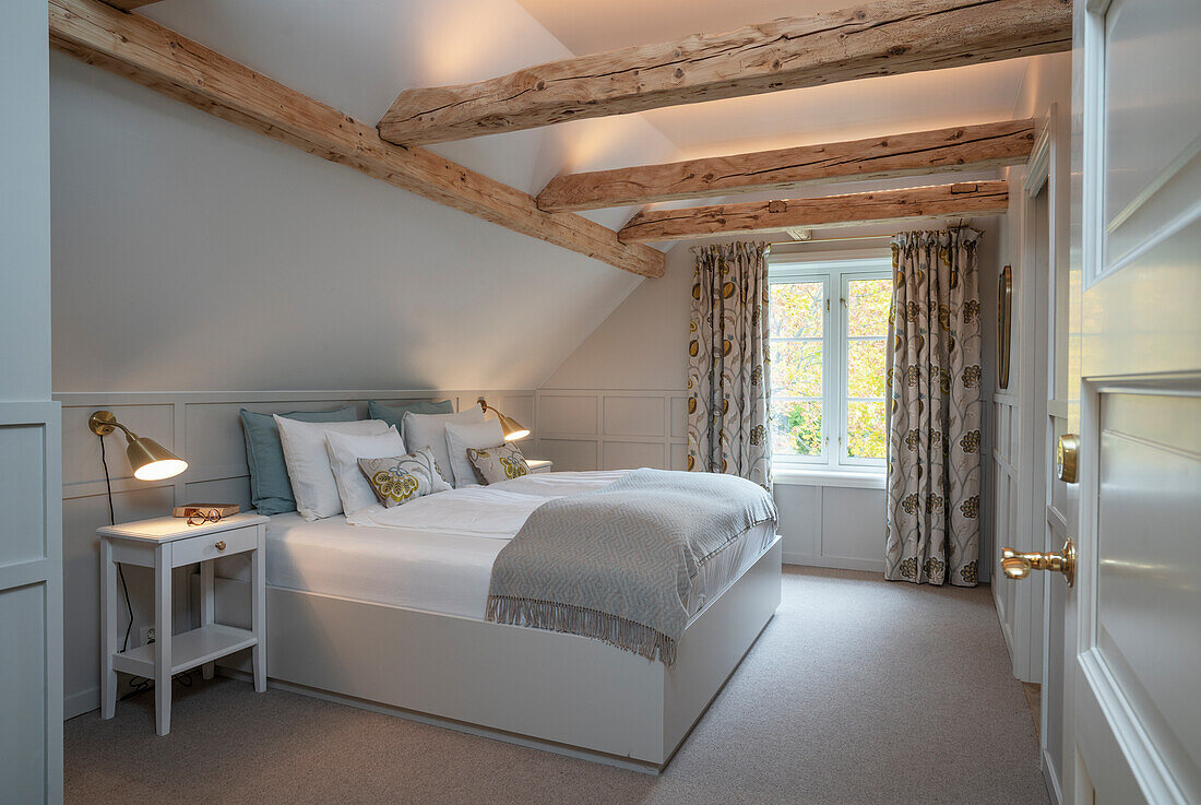 Doppelbett im Schlafzimmer mit Dachschräge und Holzbalken mit LED-Beleuchtung