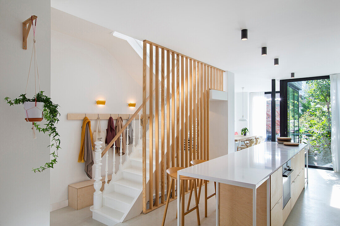 Kücheninsel mit weißer Arbeitsplatte und Treppenhaus mit Holzsprossen