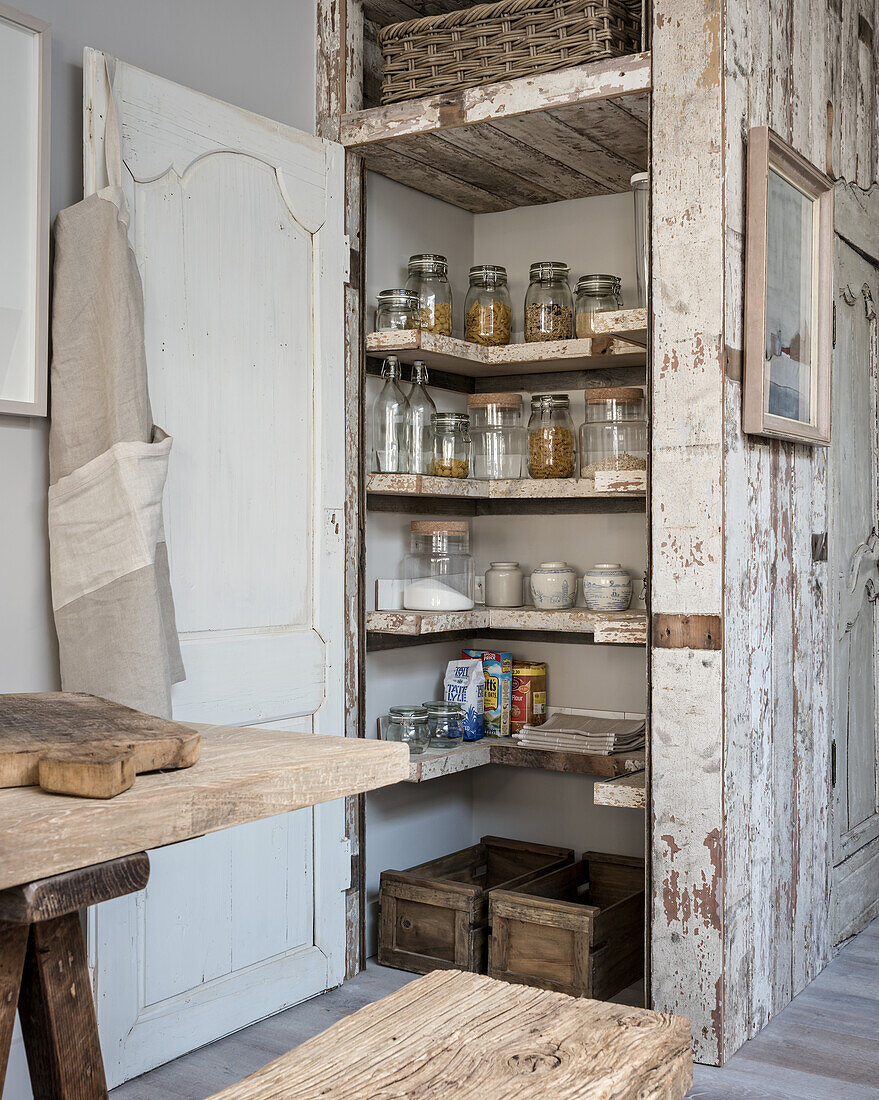 Dry store cupboard with inbuilt salvage wood shelving in kitchen with salvage wood wall panelling