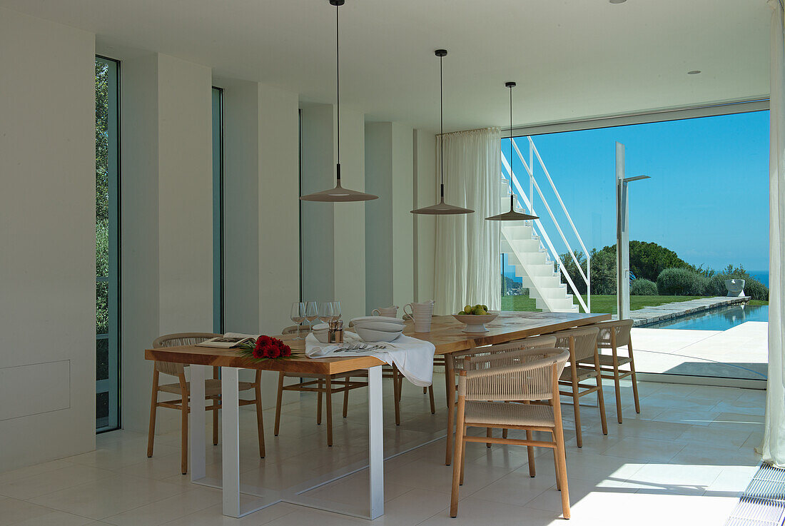 Long table and chairs in dining area with view of pool