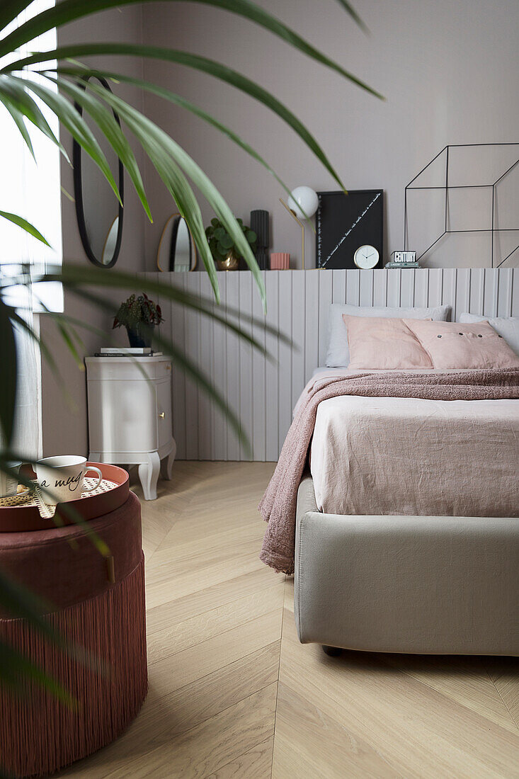 Doppelbett vor Holzvertäfelung mit Dekoobjekten im Schlafzimmer
