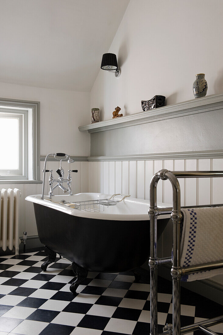 Black roll top freestanding bath in bathroom with checkered floor
