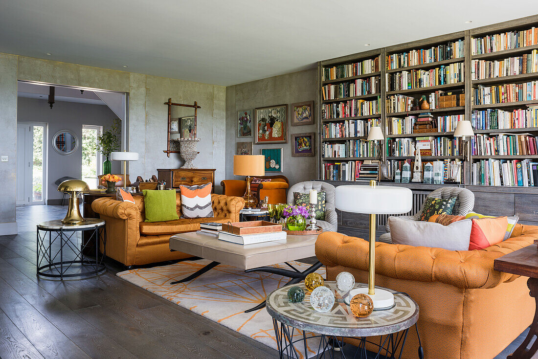 Orangefarbene Samtsofas vor Bücherwand im Wohnzimmer