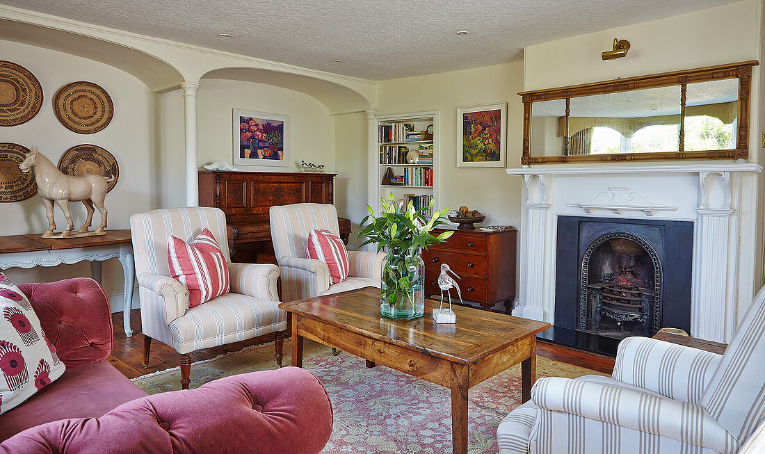 Upholstered armchair and coffee table in front of the fireplace in an English country house