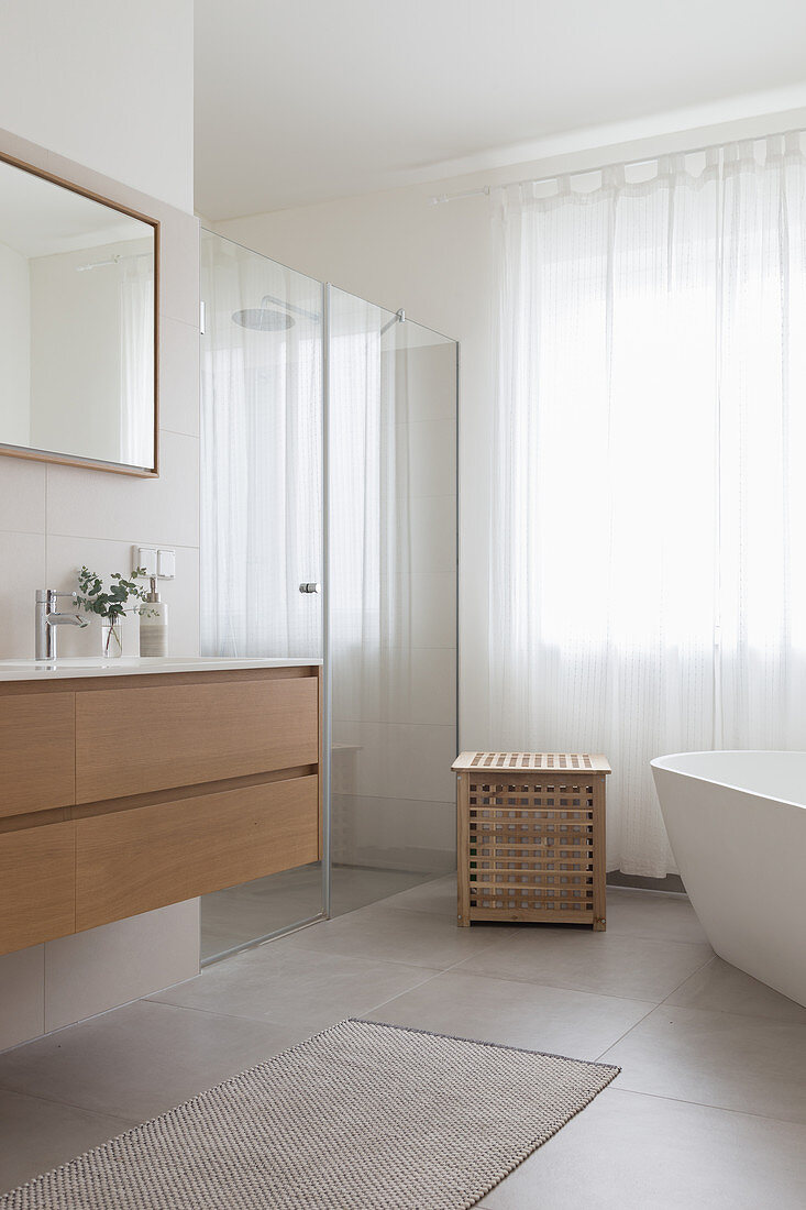 Waschtisch, Duschbereich mit Glastür und frei stehende Badewanne im Badezimmer