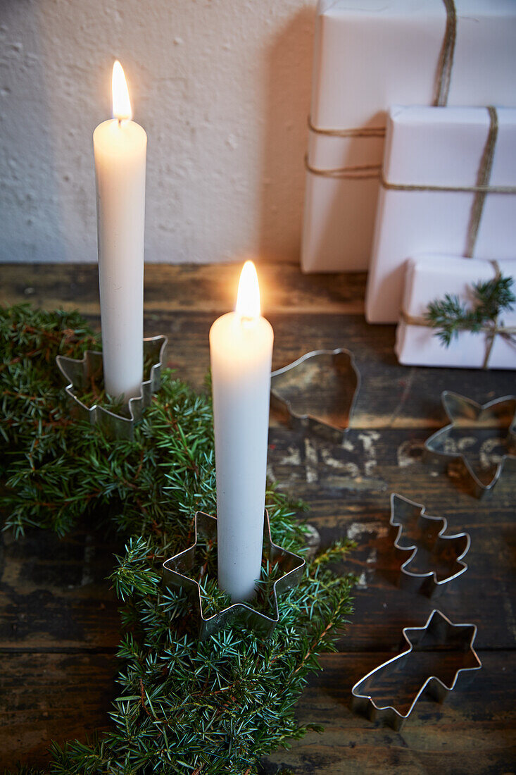 Lit candles with pastry cutters and juniper branches