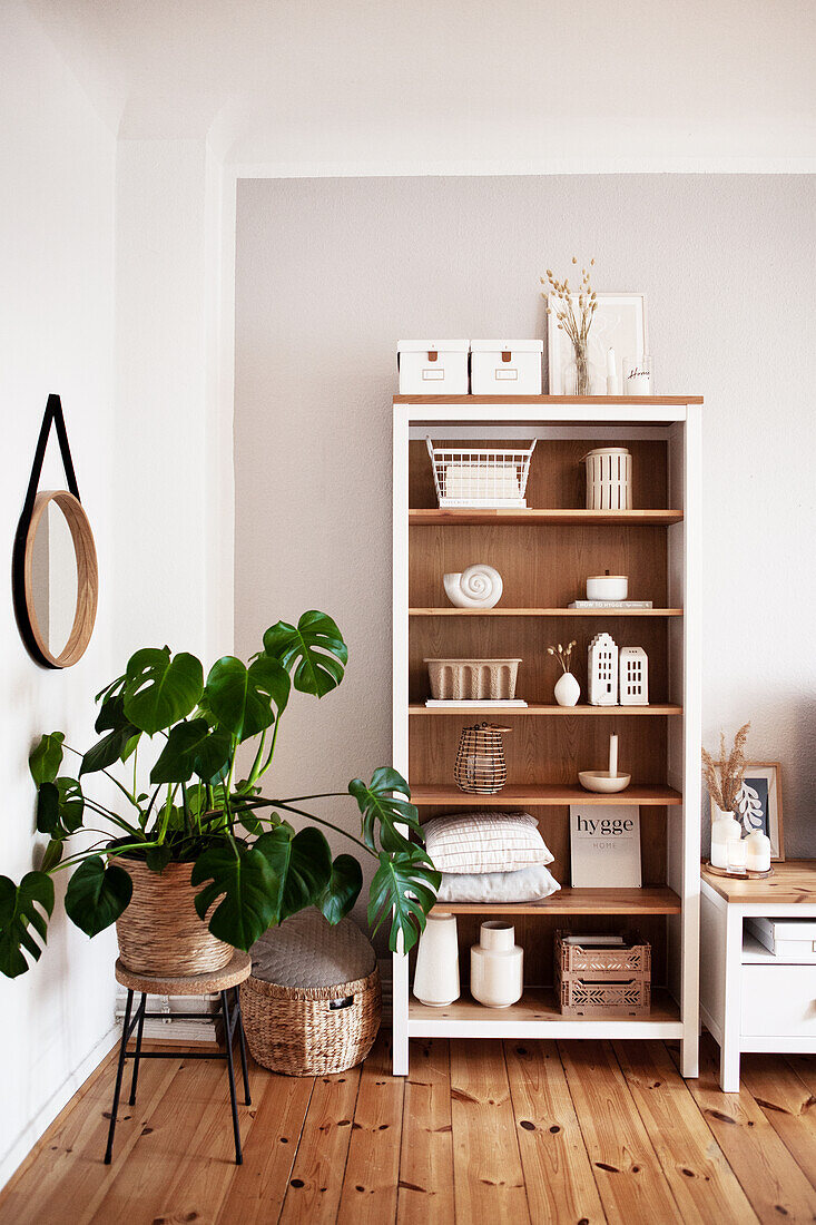 Wohnzimmer mit skandinavischem Desing: Offenes Regal mit Dekoobjekten in Weiß und Beige und Zimmerpflanze