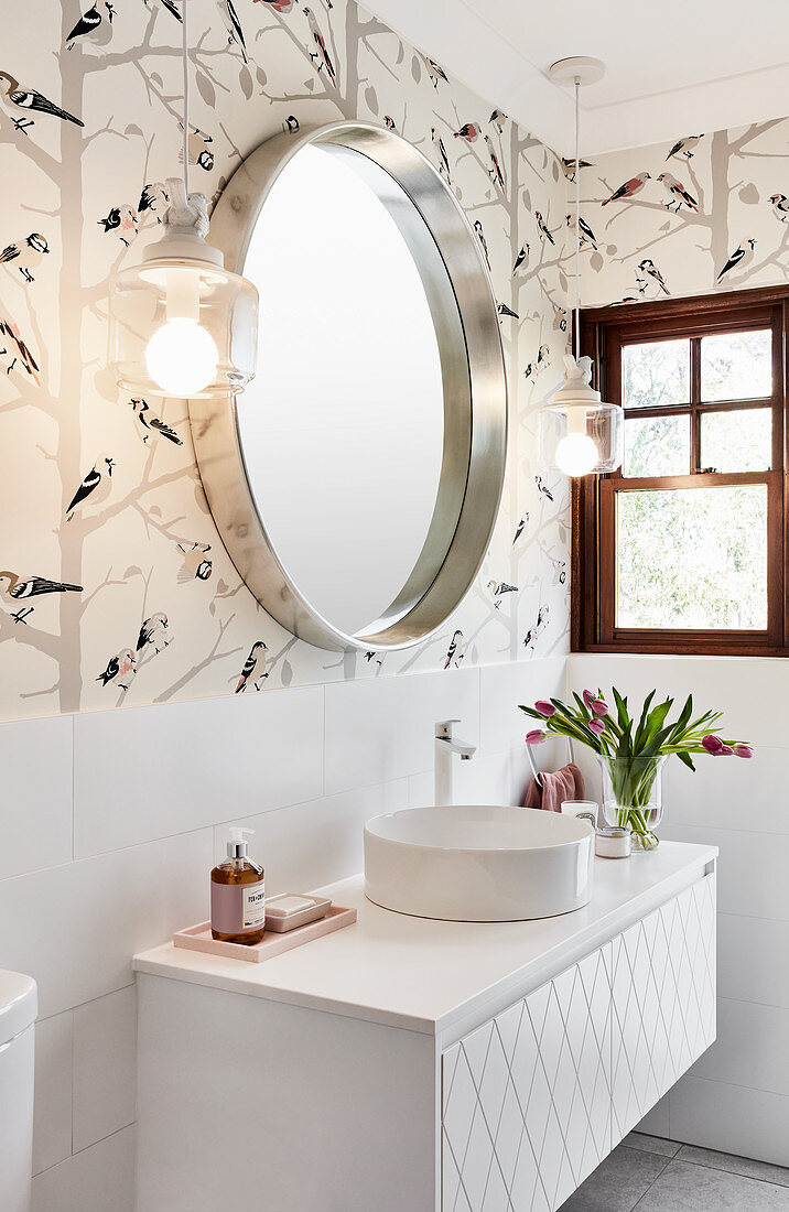 Washstand with round countertop sink below mirror and sconce lamps