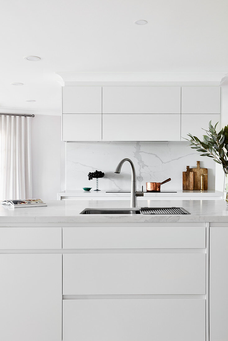 Island counter with integrated sink in elegant white kitchen