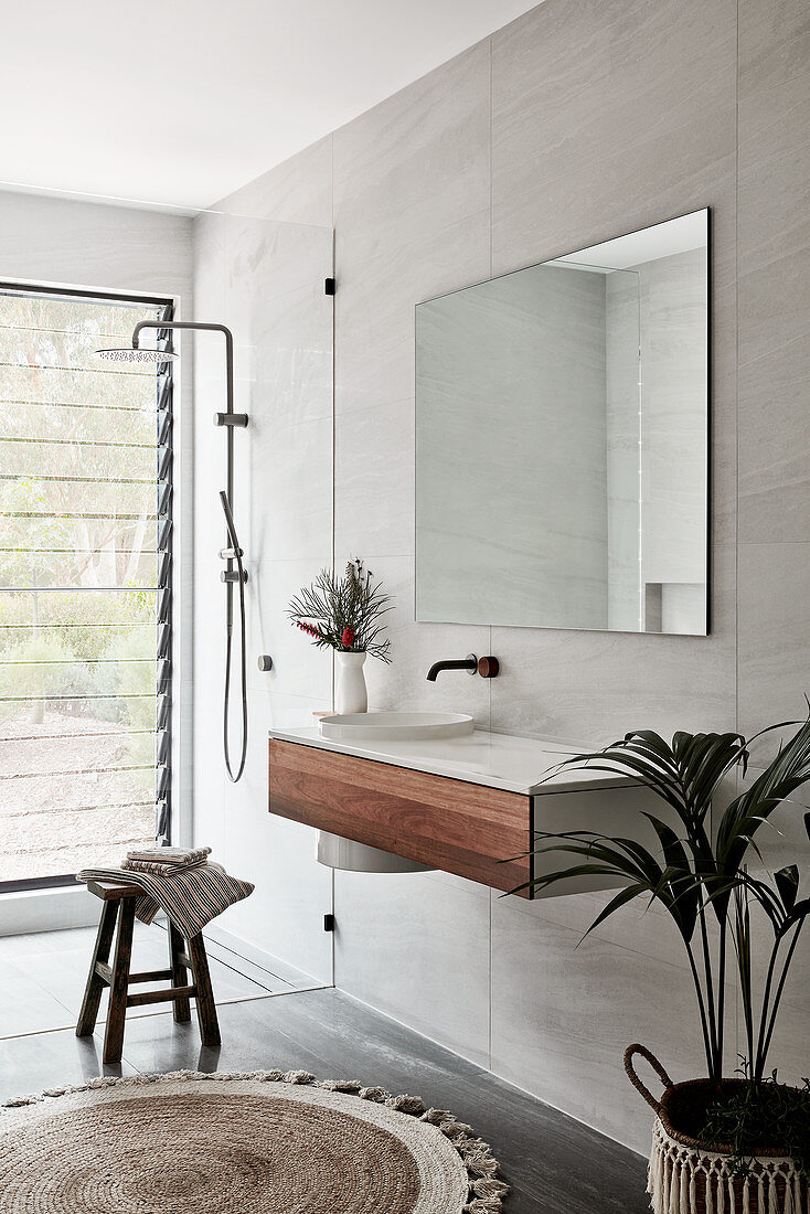 Floating washstand and mirror next to walk-in shower