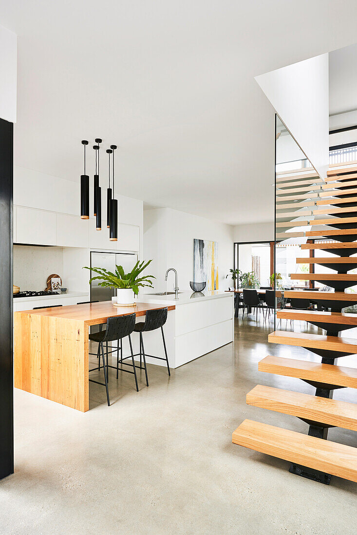 Elegante Weiße Küche mit Holztheke als Verlängerung der Kücheninsel und Treppe in offenem Wohnraum