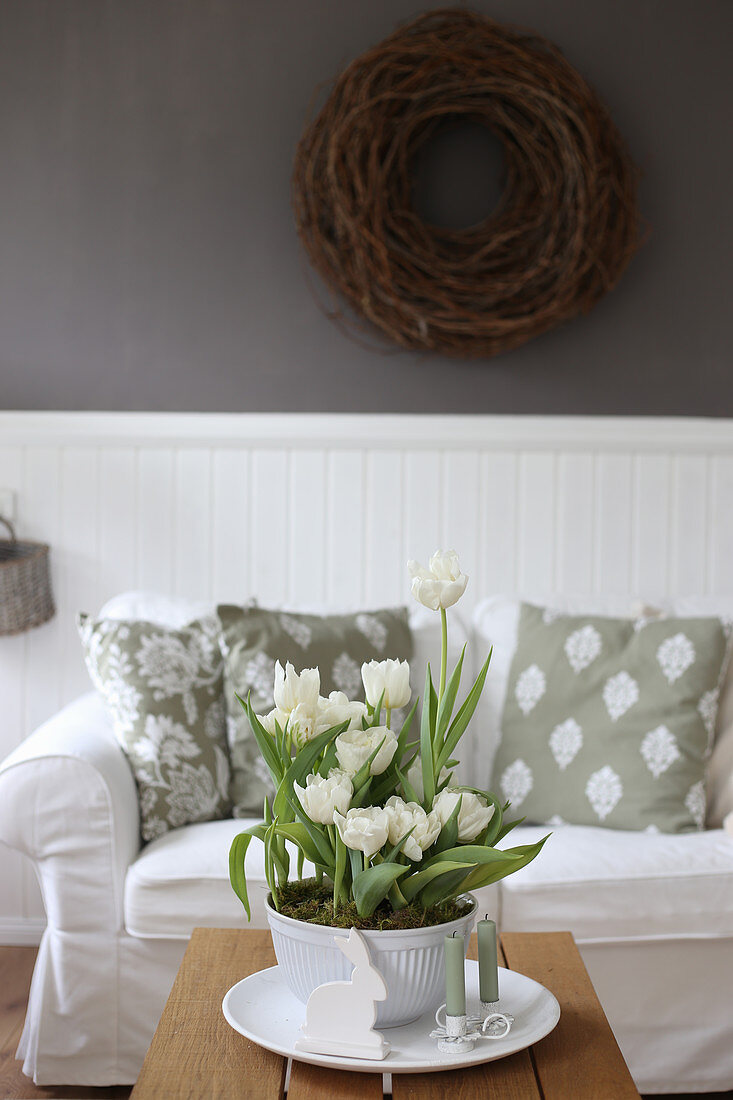 Schale mit weißen Tulpen auf dem Couchtisch im Wohnzimmer