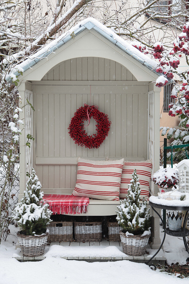 Arbour bench in winter with a berry wreath and red and white cushions