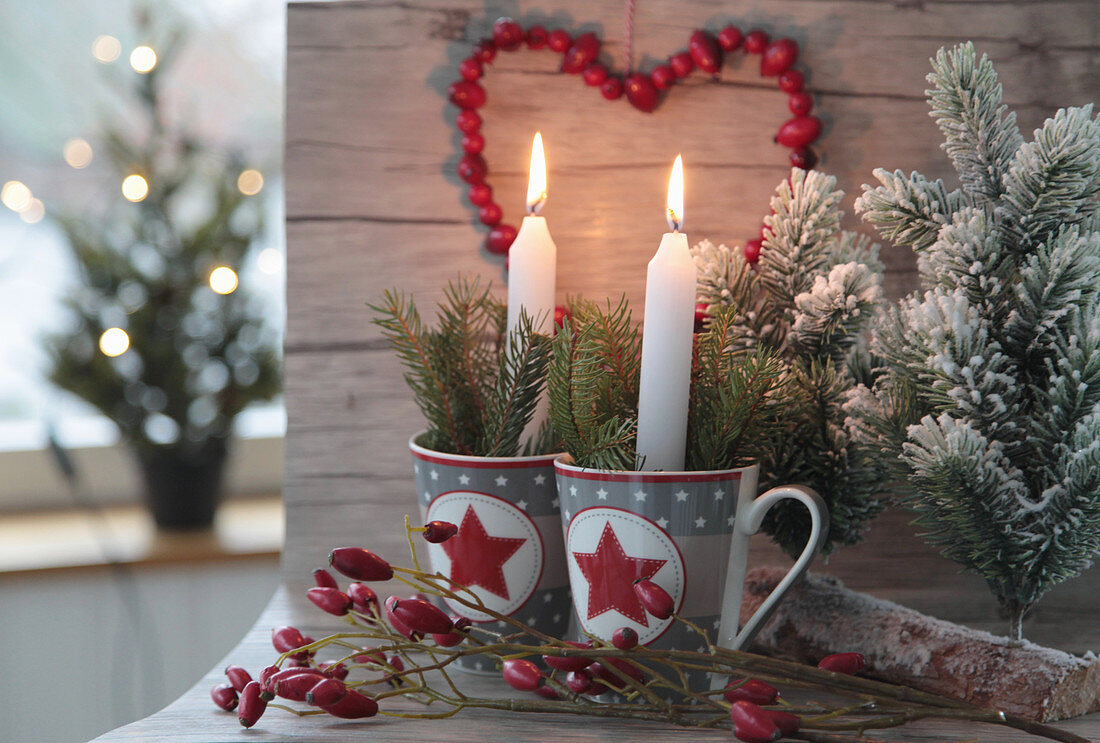 Candles and twigs in Christmas mugs with a rose hip heart