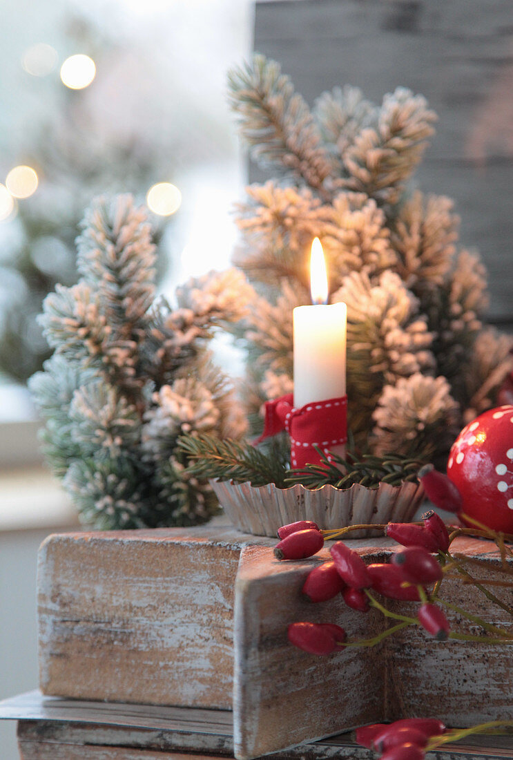 Candles in baking molds on a wooden star, Christmas tree ball, Christmas tree and rose hips