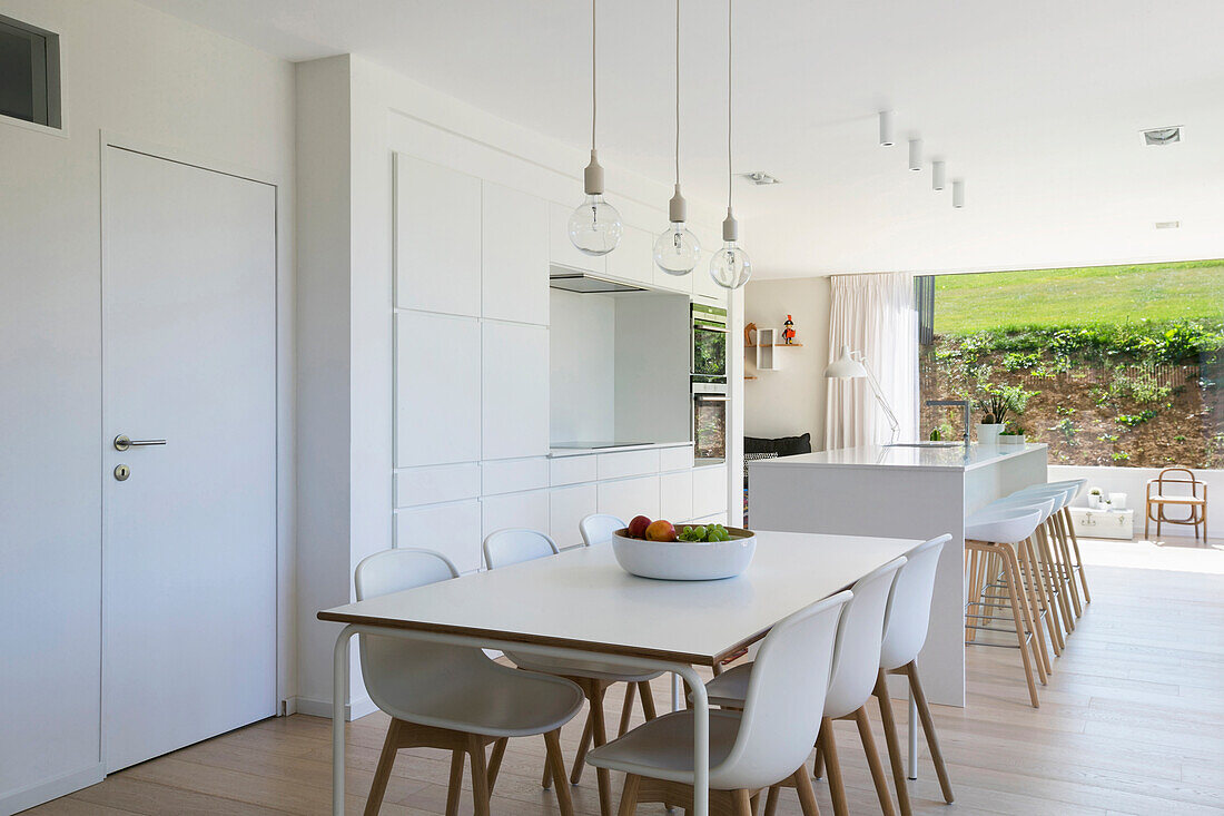 Dining area and white fitted kitchen in open-plan interior with access to terrace