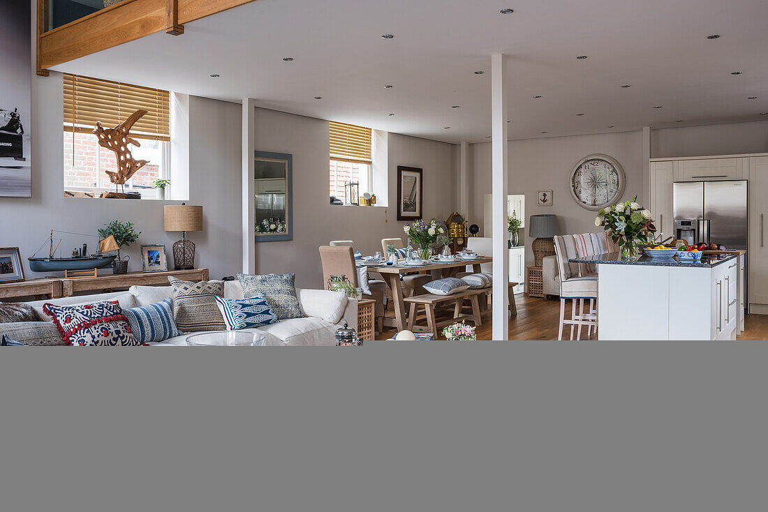 Offener Wohnraum im maritimen Stil mit Kücheninsel, Esstisch und Sofa