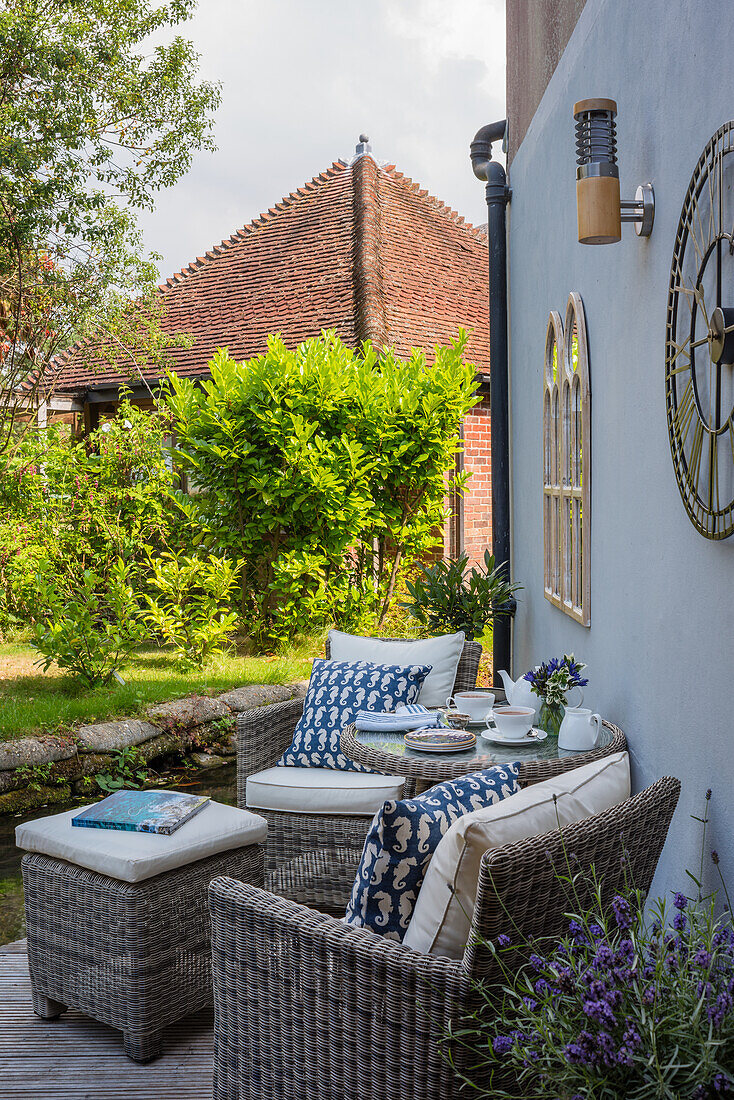 Sitting area with wicker chairs on small terrace of a house by the canal