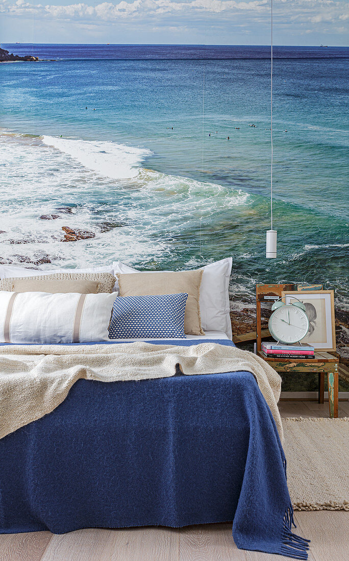 Doppelbett, Nachttisch und Pendelleuchte vor Fototapete mit Meer