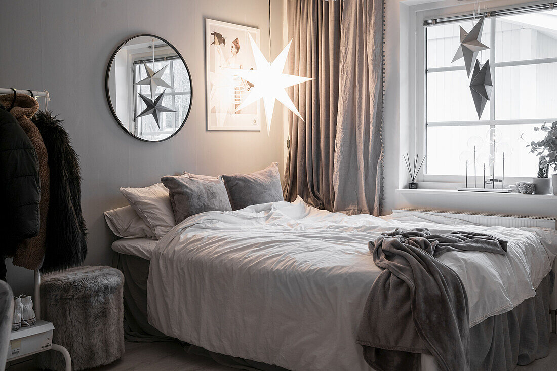 Leuchtender Stern überm Bett im winterlichen Schlafzimmer in Grau