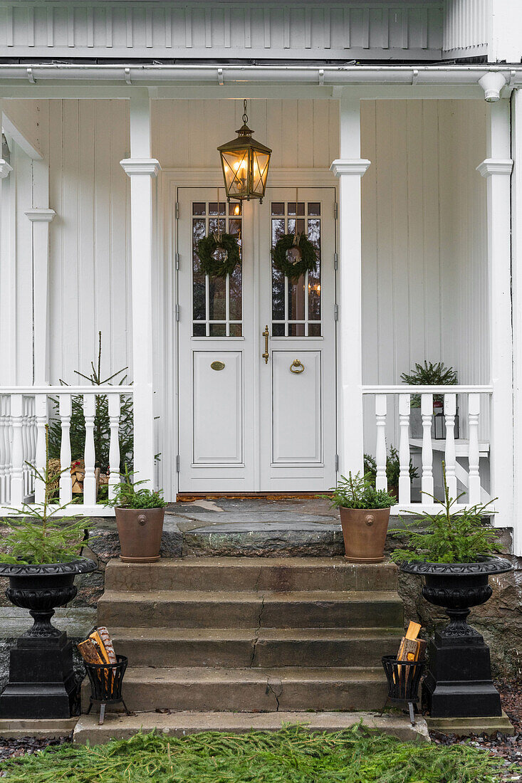 White wooden house with covered front porch decorated for Christmas