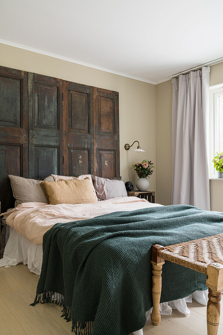 Queen size bed with old wooden doors as a headboard in a bedroom