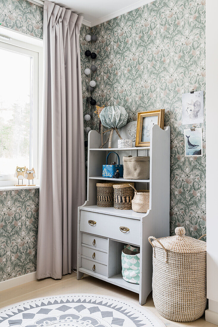 Small sideboard against a wall with floral wallpaper