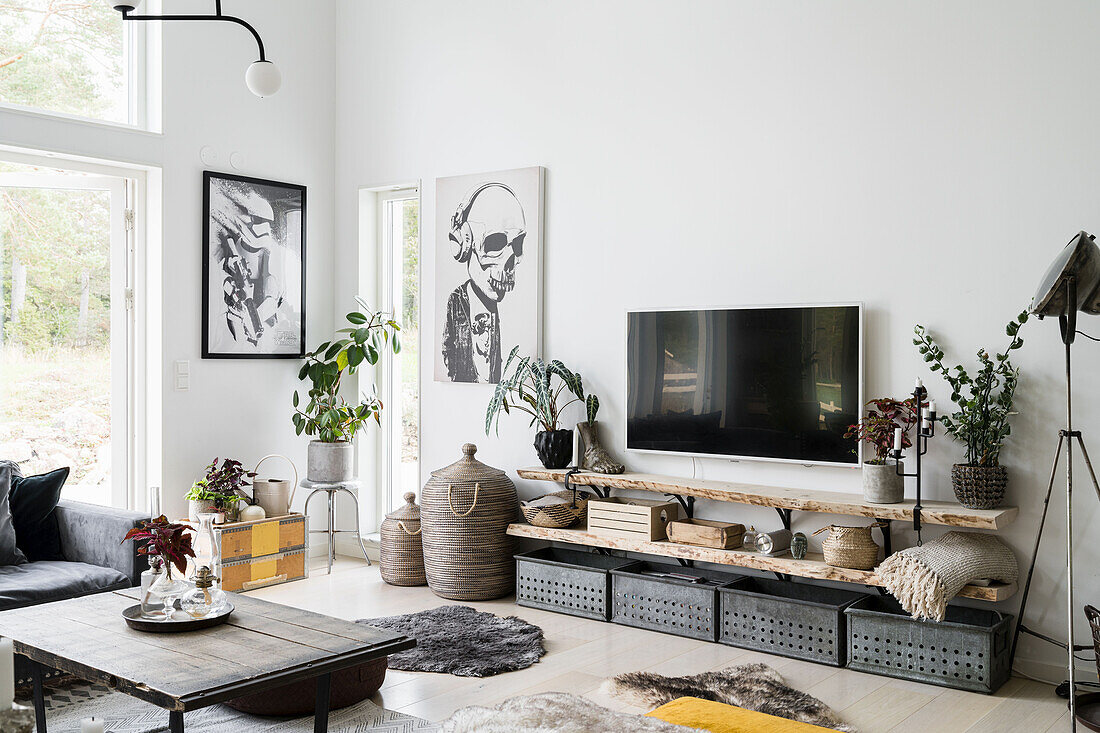 Vintage metal boxes, above wooden shelves and TV, posters on a white wall in a living room