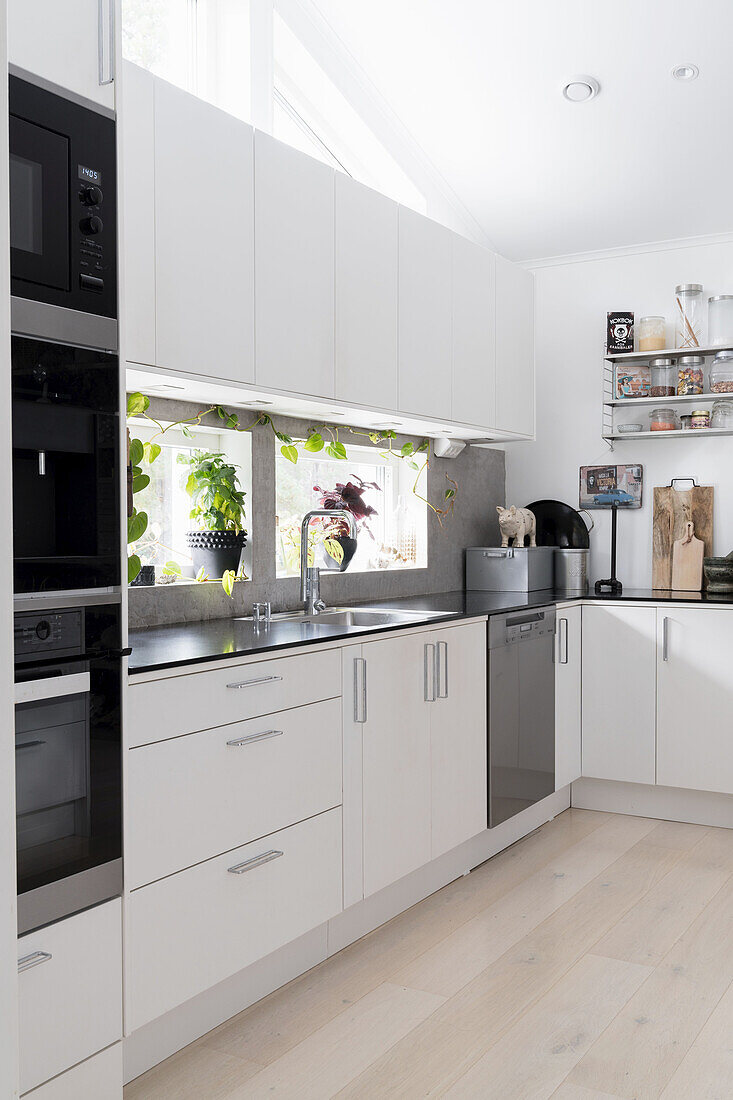 White, contemporary fitted kitchen with black counter top